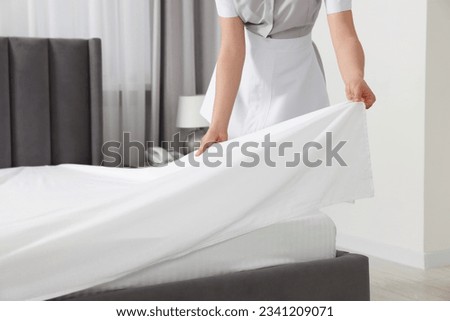 Maid making bed in hotel room, closeup