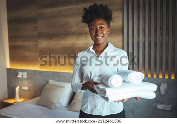 Maid putting stack of\
fresh white bath towels on the bed sheet. Room service maid\
cleaning hotel room. Maid making bed in hotel room. Change of\
towels in the hotel room