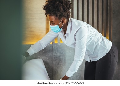 Maid Wearing Mask Cleaning Bedroom After Guests In Hotel Room. Hotel Service Concept. Maid Working At A Hotel Doing Room Service And Disinfecting Due To COVID-19 Pandemic