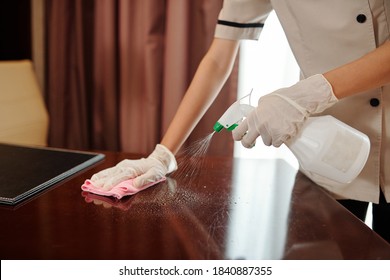 Maid Wearing Rubber Gloves When Wiping Furniture In Hotel Room With Disinfecting Spray