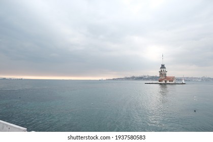 The maiden's tower (kiz kulesi) during overcast weather with sunshine reflection ans sunset in bosporus sea. Groups of seagulls flying  and golden horn silhouette background istanbul Turkey 01.03.2021