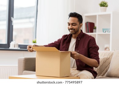 Mail Delivery, Shipment And People Concept - Happy Man Opening Parcel Box At Home