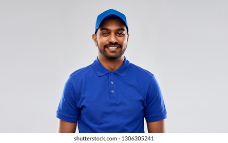 mail service, job and people concept - happy indian delivery man in blue uniform over grey background