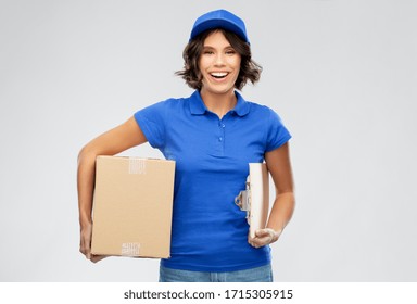 Mail Service And Shipment Concept - Happy Smiling Delivery Girl In Blue Uniform With Parcel Box And Clipboard Over Grey Background