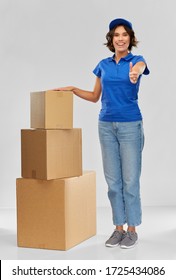 Mail Service And Shipment Concept - Happy Smiling Delivery Girl With Parcel Boxes In Blue Uniform Over Grey Background