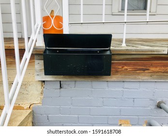 A Mailbox Is Attached To A Front Porch Of A House With A Pumpkin Behind The Box