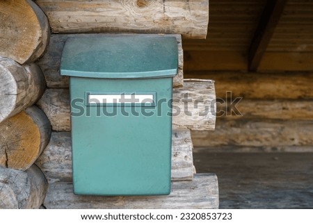 Mailbox with empty white label outside the wooden lean-to shelter in forest.