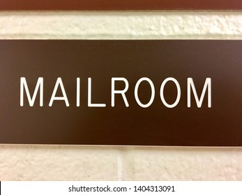 Mailroom/ Mail Room Plastic Brown Sign Attached To A Concrete Block Wall Painted Beige.