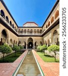 Main courtyard of the Royal Alcazar, Seville Spain, under a bright blue sky