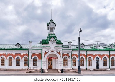 Main entrance to historic building of oldest railway station Perm 1, architectural monument of cultural heritage, Perm, Russia. Text above main entrance - Railway Station - Powered by Shutterstock