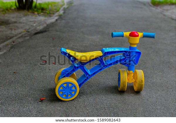The main object is a children\'s plastic\
four-wheeled bicycle painted in bright yellow and blue colors.  on\
the steering wheel a bright red sphere - a\
signal