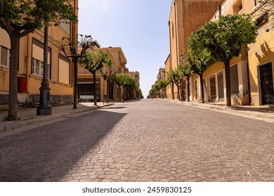 main pedestrian street of a typical Sicilian village in the early afternoon sun; no people, a small dog  - Powered by Shutterstock