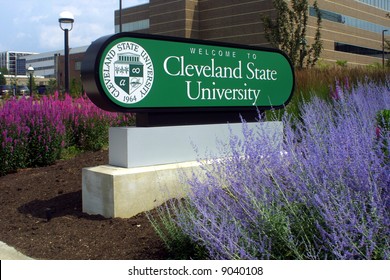 Main Sign Of Cleveland State University Surrounded By Purple And Blue Flowers.