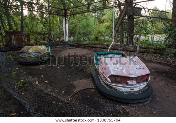 The main square of Pripyat. Abandoned\
attraction in a radioactive city. The street is overgrown with\
trees and bushes. Old toy cars in an abandoned\
park.