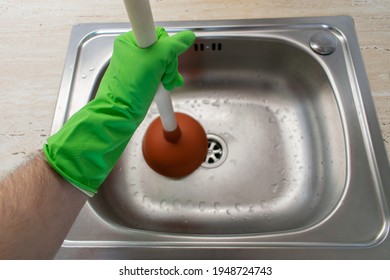 The main subject is out of focus, Solving Common Household Drain Problems, symptoms Solutions blockage plumbing kitchen sink unclog plunger force cup male man hand hold 
