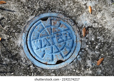 Main Water Shut-off Valve Cover On Textured Asphalt. 