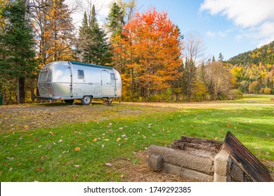 Maine USA -October 6 2014; American iconic travel trailer parked in great outdoors in shady spot under autumn color trees..
