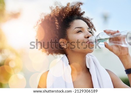 Maintaining good hydration also supports healthy weight loss. Cropped shot of a young woman enjoying a bottle of water while out for a run.