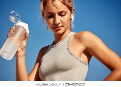 Maintaining hydration. A woman drinks water during a workout, replenishing her water-salt balance, beautiful light, a woman quenches her thirst on a sunny day - Powered by Shutterstock