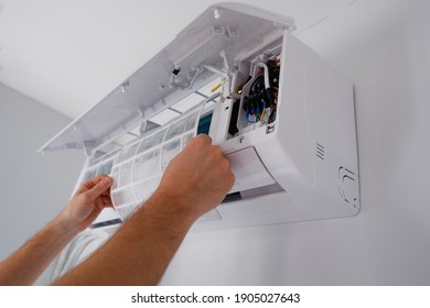 Maintenance of the air conditioner. A technician is cleaning the filter. View of the hands. - Shutterstock ID 1905027643