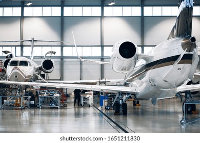 Maintenance Of Airplane In Large White Hangar. Modern Private Jet At The Factory