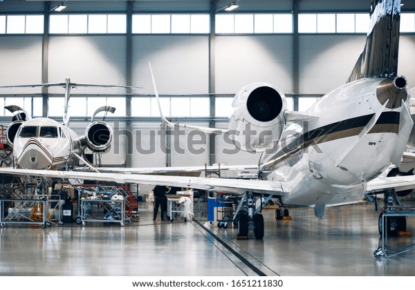 Maintenance of airplane in large white hangar.\
Modern private jet at the\
factory