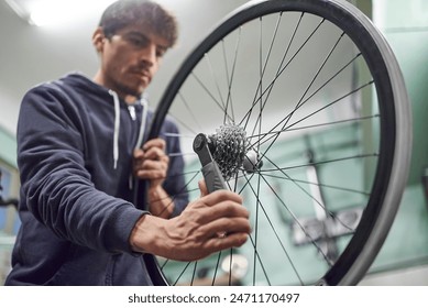 Maintenance of a bicycle: hispanic repairman assembling the sprocket set of a bike wheel at his repair shop. Real people at work. - Powered by Shutterstock