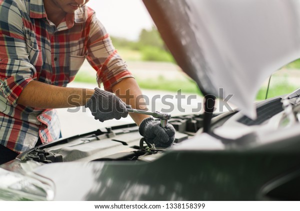 maintenance car using screwdriver. Traveler man hands\
holding tools fixing repair car engine. Close up mechanical man\
dirty hands holding tools using screwdriver maintenance car vehicle\
service. 