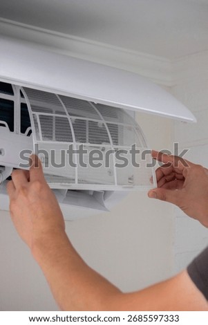 Maintenance Complete. Technician Installing Clean Air Filter in Air Conditioner.