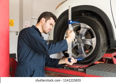 Maintenance Engineer Checking Alignment Of Tire With Camber Caster Adapter In Garage