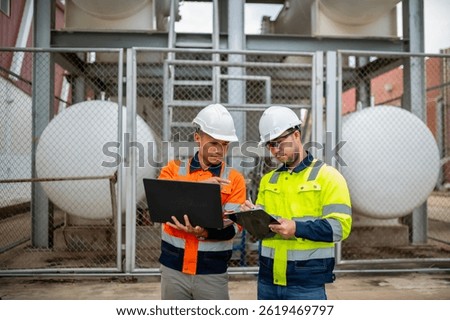 A maintenance engineer is checking the condition of a large gas cylinder using a laptop