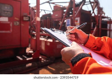 Maintenance engineer performs audit and inspection the power generator machine (as background) at the oil refinery plant working site. Industrial safety working wit people action, selective focus.