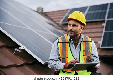 Maintenance engineer working on digital tablet while checking solar panel system on the roof. 