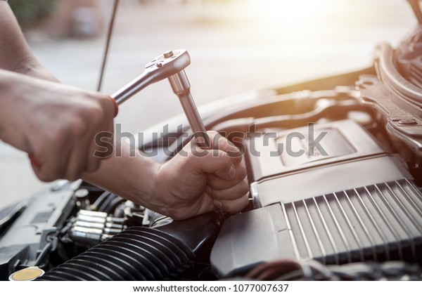 Maintenance or fixing a car, Hands of car\
mechanic with wrench  for auto repair service in garage. Check and\
repair the condition of the car\
engine.