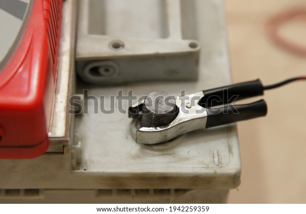 Maintenance free car battery\
negative pin with black terminal cleat of automatic charger\
closeup