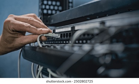 Maintenance of LAN or web servers. Close up of system administrator connecting cables with server rack, working in server room. Operation of information systems and networks. Data storage center.