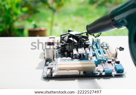 maintenance mainboard or motherboard concept. engineer cleaning a mainboard or motherboard hardware computer desktop or pc outdoor. technical cleaning of motherboard or mainboard with Electric Blower