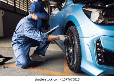 Maintenance male checking tire service via insurance system at garage, Safety vehicle to reduce accidents before a long travel, Blue car of man transportation lifestyle  
