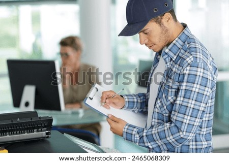 maintenance man checks a printer at work