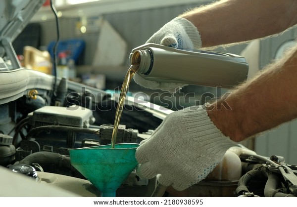 Maintenance\
of a passenger car in a service center. An auto mechanic performs\
the work of replacing the oil in the\
engine.