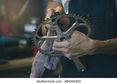 Maintenance And Repair Bike Concept. Hands Of Technician (worker) Repair, Maintenance, And Clean Bicycle Parts (chain Ring) In Workshop.A Small Business Owner In Bicycle Store.