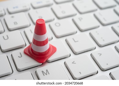 Maintenance, Repair, Under Construction In Computer System From Virus Or Ransomware Concept. Close Up Orange White Traffic Warning Cones Or Pylon On Keyboard Computer Background With Copy Space.