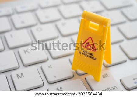 Maintenance, repair, update software in computer system from virus or ransomware concept. Close up yellow warning sign "Repair in progress"on white keyboard computer background copy space.