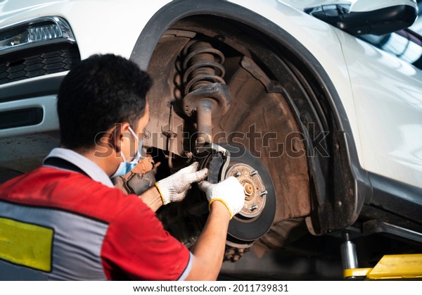 Maintenance, replacement of brake pads and car\
repairs in the service center. Close-up of a mechanic\'s hand\
replacing brake\
pads.