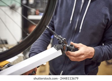 Maintenance service in a bicycle workshop: unrecognizable person aligning a bike wheel using a truing stand. Real people at work. - Powered by Shutterstock