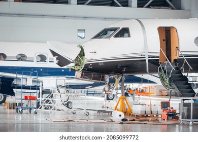 Maintenance And Service Check Of An Airplane In The Large White Hangar. Airplane Workshop And Repair Station