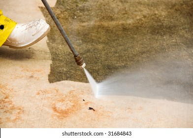 Maintenance Worker Cleaning Old Dirty Driveway With A Pressure Cleaner