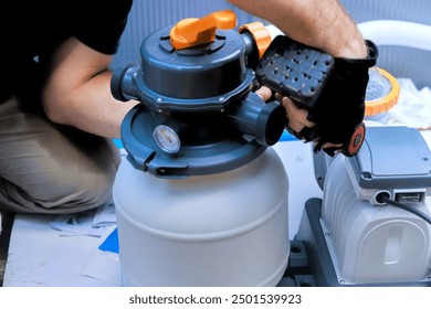 Maintenance worker service assembles sand filter system tank, equipment for swimming pool cleaning water