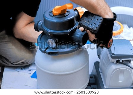 Maintenance worker service assembles sand filter system tank, equipment for swimming pool cleaning water