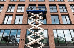 Maintenance Workers Are Repairing A Modern Building Facade From An Elevating Scissor Lift Aerial Work Platform